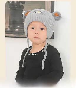 Détail du bonnet en tricot gris pour enfant avec cache-oreilles et oreilles d'ours