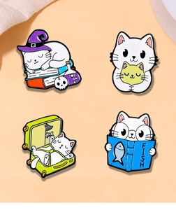 Detail view of four cute magic cat enamel pins with wizard hat and suitcase designs