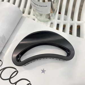 Matte black oversized crescent claw clip on book for elegant minimalist hair styling