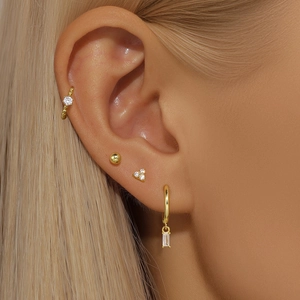 Close-up of gold geometric s925 silver earring set with crystals on a female model