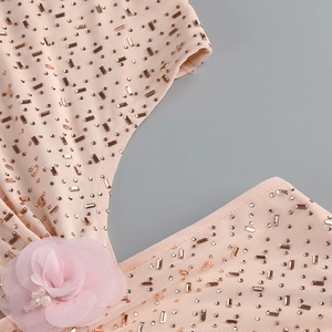 Détail d'une robe de soirée rose avec fleurs 3D faites main et strass scintillants