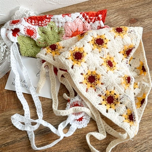 Detailed macro shot of handmade floral crochet headscarves on a rustic wooden table