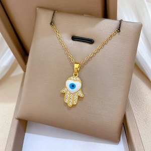 Detailed view of gold Fatima Hand necklace with sparkling zircons in a jewelry box