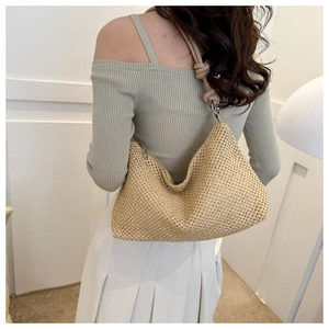 Detail of beige woven hobo bag showing texture and knotted strap on a model