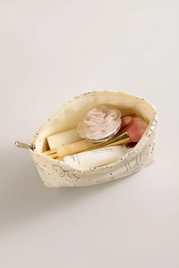 Spacious interior of cream bow makeup bag showing cosmetic bottles and floral detail