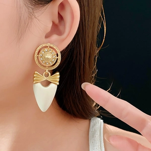 Close-up of vintage gold earrings with bow design and heart pendant worn by model