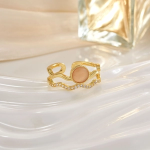 Close-up of golden double-layer ring featuring a pink opal stone and zircon accents