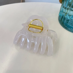 Close-up of cream white matte hair claw clip with golden spring on a clean background