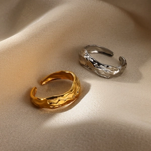 Detail of gold and silver snake rings with irregular lava texture on silk fabric