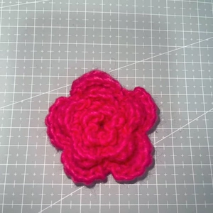 Close-up of a 7cm bright pink hand-knitted three-layer crochet flower for accessories