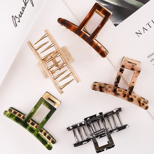 Detail view of five acetate hair claws in amber, marble, green, and leopard patterns