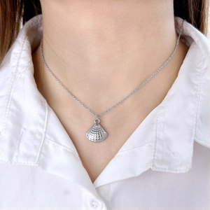Gros plan d'un collier pendentif coquillage argenté porté par un mannequin en chemise