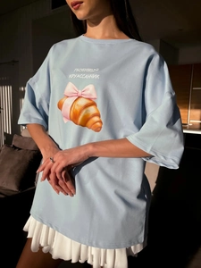 Λεπτομέρεια από γαλάζιο βαμβακερό T-shirt με στάμπα κρουασάν και ροζ φιόγκο
