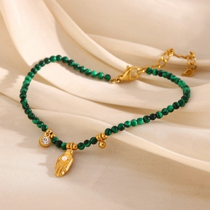Close-up of 18K gold hand pendant and green stone beads on minimalist bracelet