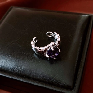 Detail of silver twisted open ring with a purple oval gemstone on black leather box