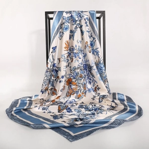 Elegant ivory silk square scarf with blue floral and butterfly print hanging on a stand