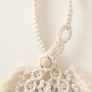Macro detail of hand-woven beige cotton rope curtain tieback with a round wooden bead