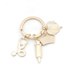 Macro view of golden medical keychain featuring stethoscope, syringe and heart charms