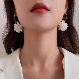 Elegant white floral drop earrings with gold twisted hooks worn by a model in close-up view