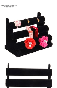 Detailed side view of a black velvet three-tier cylinder jewelry and bracelet display stand