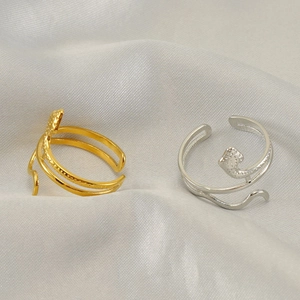 Minimalist gold and silver hollow snake shaped open rings on white silk background