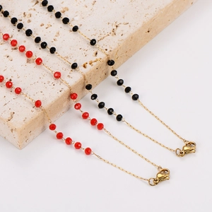 Detail of colorful beaded necklaces with red and black crystals on a white stone base