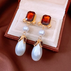 Macro view of vintage gold drop earrings with red gemstones and water-drop pearls