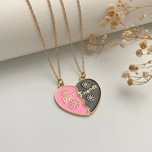 Close-up of split heart Best Friends necklaces with pink and black enamel floral charms