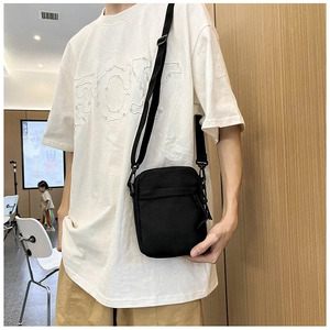 Detail of the durable black canvas shoulder bag with adjustable strap worn by a model