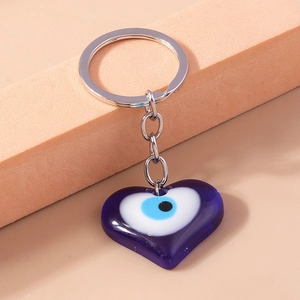 Detailed view of a purple resin heart charm with a blue Greek Evil Eye and silver key ring