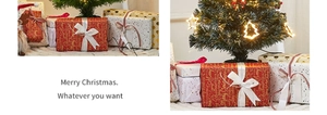 Detail of red and gold Merry Christmas gift wrapping paper under a festive lit tree