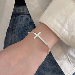 Close-up of a minimalist S925 sterling silver cross charm on a fine box chain bracelet