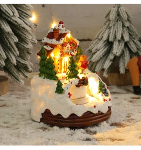 Detailansicht eines leuchtenden Weihnachts-Musikhauses mit warmen LEDs und verschneitem Sockel.