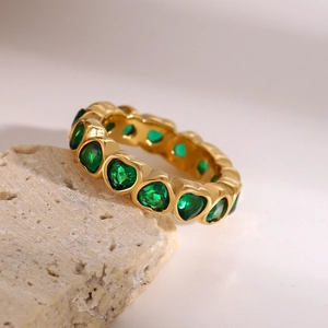 Detailed close-up of gold stainless steel ring with continuous heart-cut green emerald stones