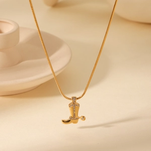 Vue macro du pendentif botte de cowboy doré avec strass sur chaîne serpent chic