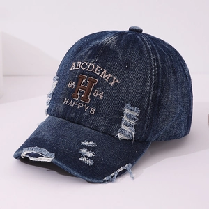 Detailed close-up of distressed denim baseball cap with vintage embroidery and ripped edges