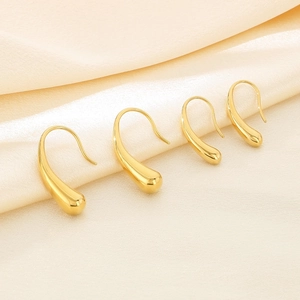 Detailed macro shot of gold teardrop earrings in two sizes on beige silk fabric