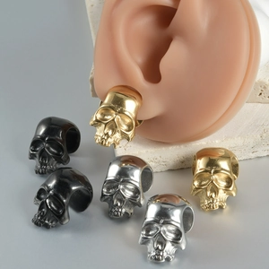 Detailed view of skull ear cuffs in gold, silver, and black on a silicone ear model