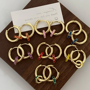 Detailed view of colorful enamel hoop earrings in rainbow colors on a wood base
