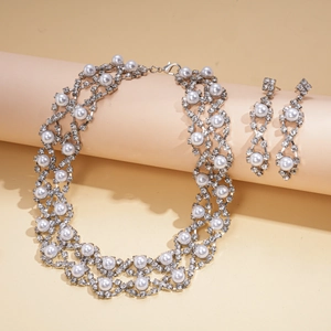 Detailed view of rhinestone flower necklace and pearl earrings set on display stands