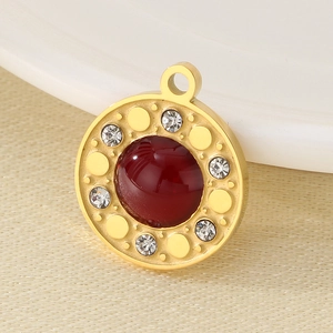 Close-up of golden round pendant with deep red gemstone and micro-pave crystals
