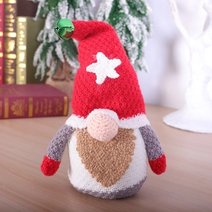 Knitted Christmas Gnome plush with red and white hat and bell on wooden table