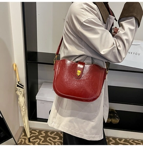 Detail of vintage burgundy saddle bag featuring glossy finish and gold buckle closure
