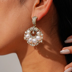 Macro view of vintage gold hollow earrings with faux pearls and sparkling crystals