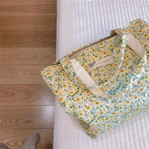 Detailed close-up of a floral cotton tote bag with a small fabric tag and cream strap