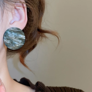 Gros plan de boucles d'oreilles rondes en acrylique effet marbre gris sur modèle