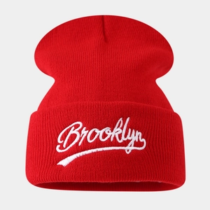 Close-up of bright red ribbed knit beanie with white Brooklyn embroidery on the cuff