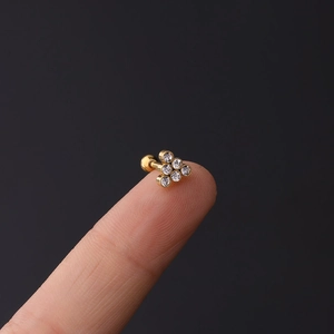 Macro shot of 16G gold cartilage stud with six zircons in triangle cluster on fingertip