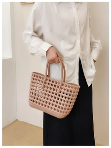 Detailed close-up of pink woven hollow jelly beach bag held by a model in casual style