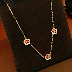 Dettaglio della collana a fiori placcata oro 18K con rubini e zirconi su supporto in velluto